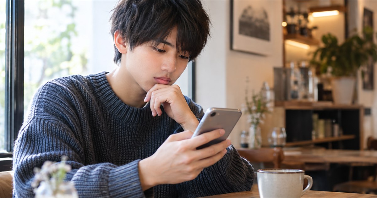 カフェでスマートフォンを使い学校の評判を確かめる日本人高校生