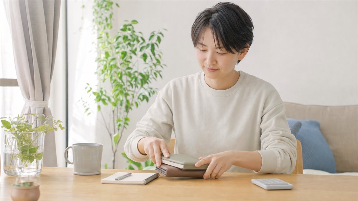 料金の確認を終えて落ち着いた表情で財布とノートをしまう20代の人物
